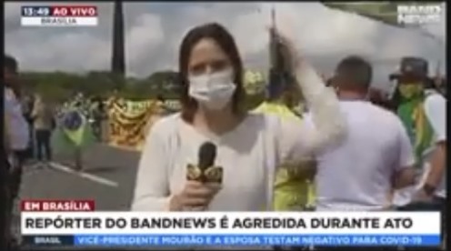 Apoiadora de Bolsonaro dá bandeirada na cabeça de repórter em ato.